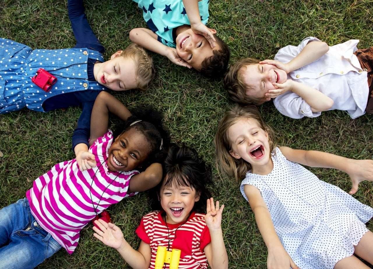 group-of-kindergarten-kids-lying-on-the-grass-at-park-and-relax-with-smiling.jpg